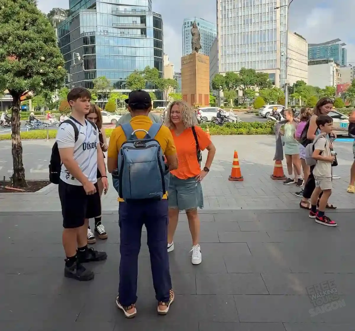 A local Free Walking Tours Saigon guide explains the city to a small group of travellers in front of the Tran Hung Dao Monument in District 1