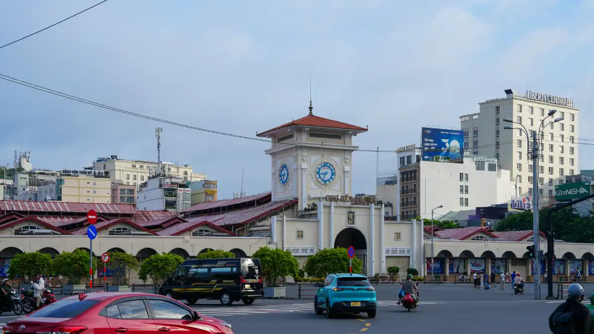 Ben Thanh Market south gate with the iconic clock tower and red-tile roof seen from the roundabout in District 1, Ho Chi Minh City