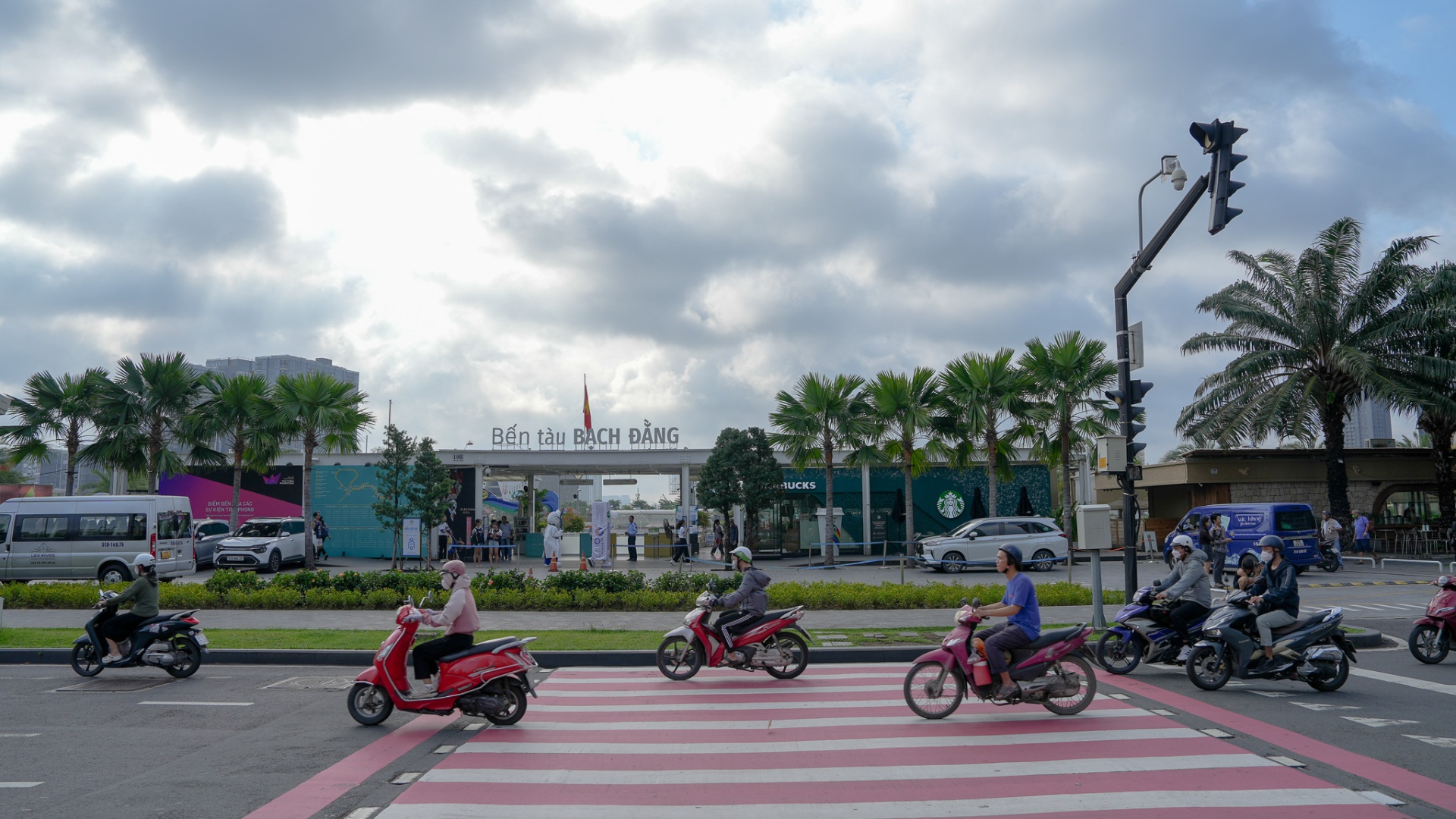 Bach Dang Wharf entrance with the 'Bến tàu Bạch Đằng' sign, palm trees and morning traffic along the Saigon riverfront in District 1, Ho Chi Minh City