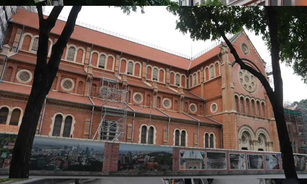 Notre Dame Cathedral Saigon red-brick French colonial facade seen through trees in District 1, a landmark on the Free Walking Tour Saigon