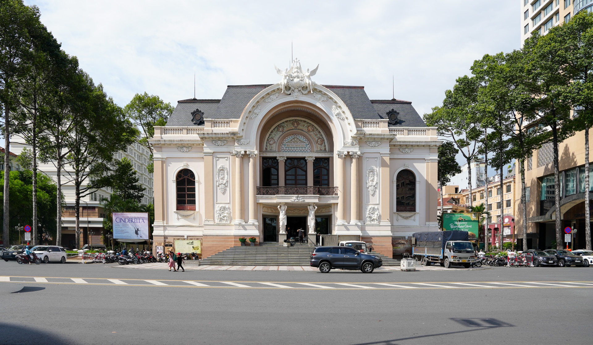 Saigon Opera House (Municipal Theatre of Ho Chi Minh City) — French colonial Beaux-Arts façade with caryatids, arched window and trees lining Lam Son Square in District 1