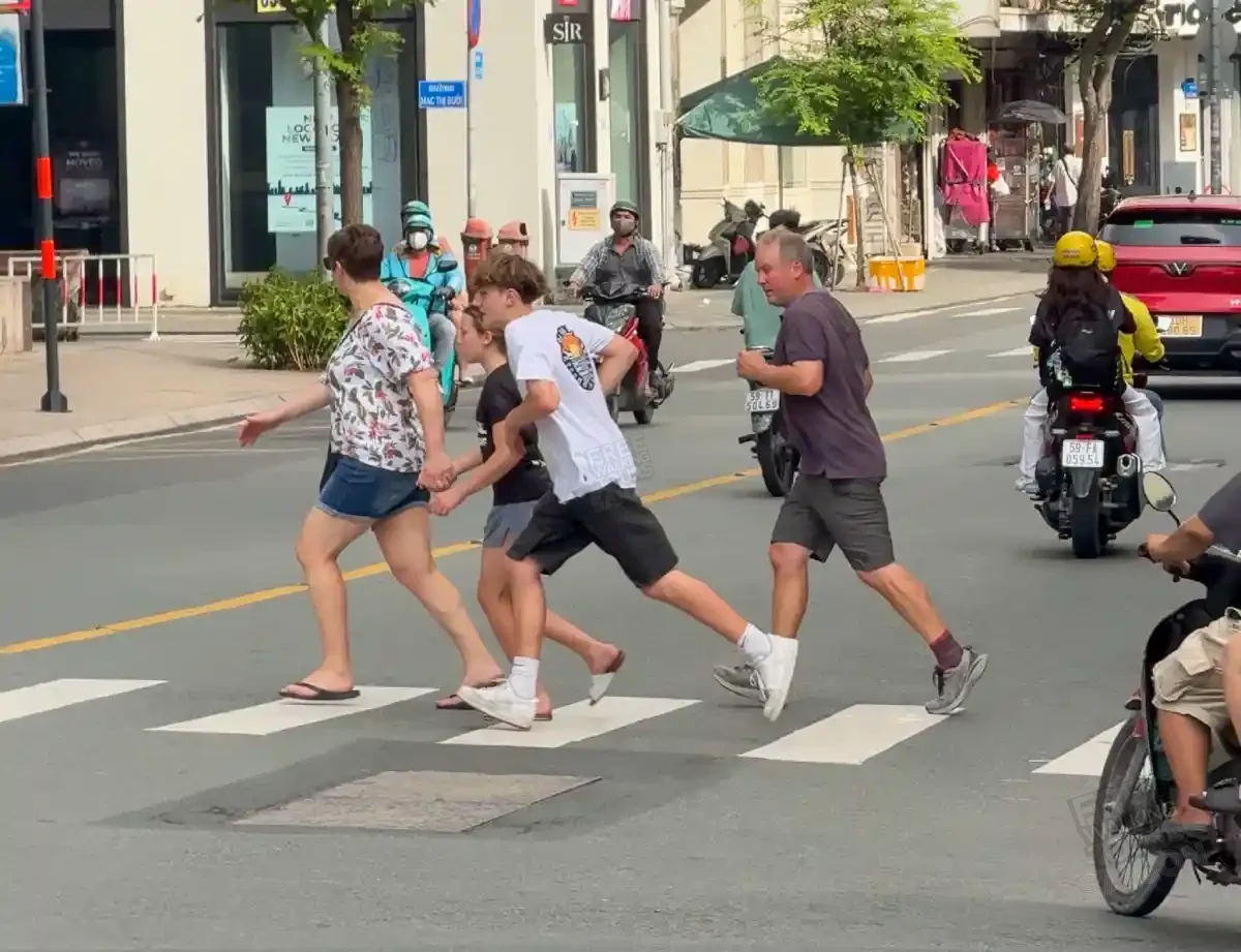 Foreign tourists running across a District 1 crosswalk in Saigon while motorbikes swerve to avoid them — an example of the most common pedestrian mistake