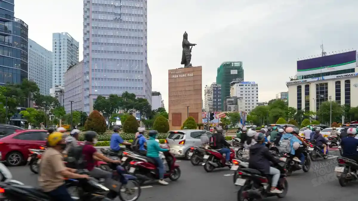 Evening rush hour around the Tran Hung Dao Monument roundabout in District 1, Saigon — hundreds of motorbikes flowing past the bronze statue