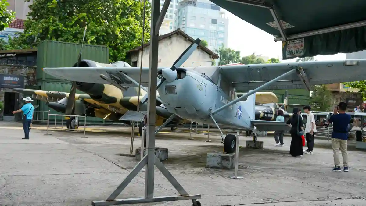 US military aircraft on display in the outdoor courtyard of the War Remnants Museum in Ho Chi Minh City, with visitors walking around the exhibit
