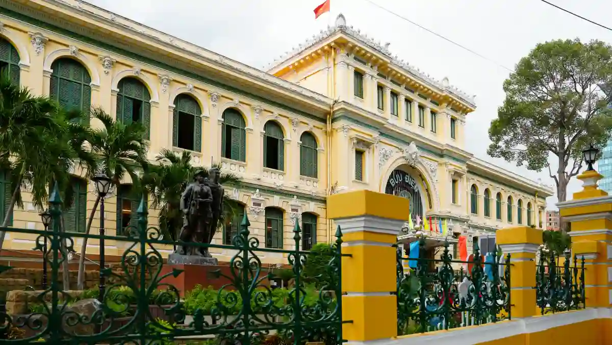 Side view of the Saigon Central Post Office showing French colonial architecture, statue and ornate iron fence in District 1, Saigon