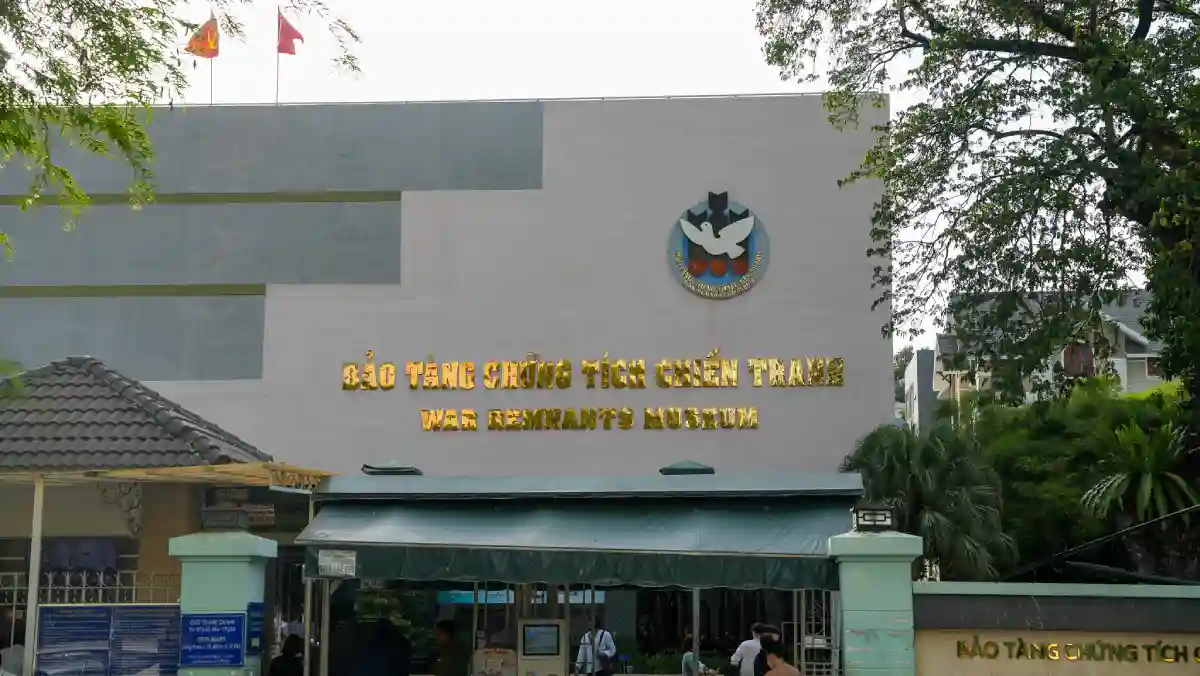 Façade of the War Remnants Museum in Ho Chi Minh City with the Vietnamese and English museum name in gold lettering and two red Vietnamese flags above