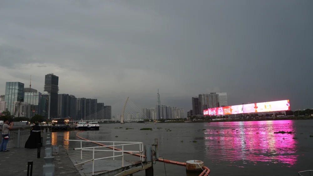View from Bach Dang Wharf across the Saigon River at dusk, showing Ba Son Bridge, the Thu Thiem skyline and Landmark 81 with pink LED reflections on the water